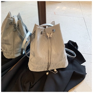 Detail of silver drawstring bucket bag with pearl accents and metal butterfly clasp