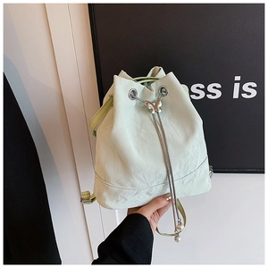 Detail of light green drawstring bucket bag with butterfly slide and pearl tassel