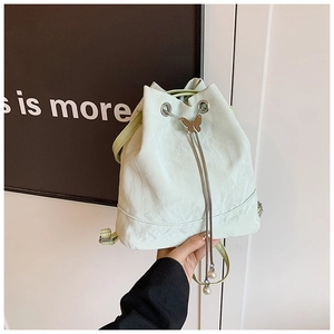 Detail of light mint bucket bag with pleated texture, silver butterfly buckle and pearl drawstring