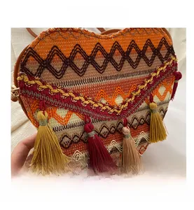 Detailed macro view of bohemian woven heart bag with colorful patterns and long tassels
