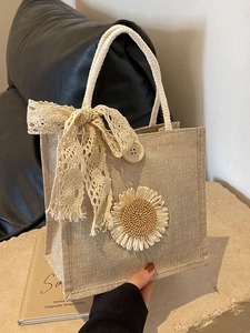 Chic beige linen lunch bag with lace bow and sunflower decoration in a hand-held view