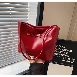 Close-up of bright red patent leather handbag featuring a chic tonal bow decoration