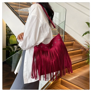 Dettaglio della borsa tote bordeaux con lunghe frange e occhielli metallici dorati lucidi