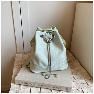 Detail of mint green bucket bag with metallic butterfly buckle and pearl drawstring