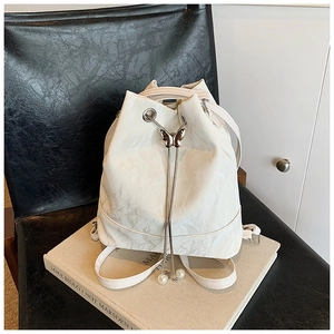 Detail of white bucket backpack featuring metal butterfly lock and pearl drawstring charms