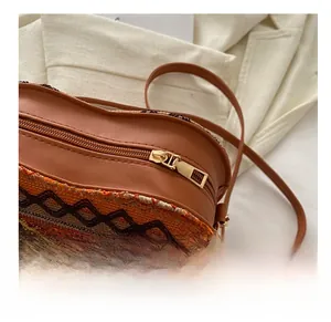 Close-up of golden zipper and ethnic woven heart bag with colorful bohemian tassels