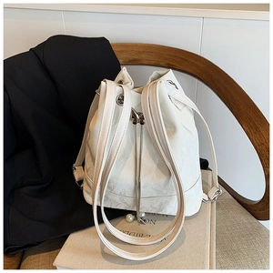 Close-up of white bucket bag with drawstring chain and elegant pearl pendants detail