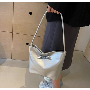 Close-up of a silver bow-accented shoulder bag featuring a pearlescent leather texture