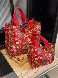 Red canvas tote bag with vintage floral patterns on a stone surface in a home setting