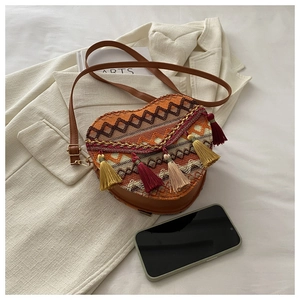 Detail of woven heart-shaped crossbody bag with geometric patterns and colorful tassels