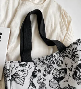 Gros plan des poignées noires et de l'imprimé papillon sur un sac fourre-tout