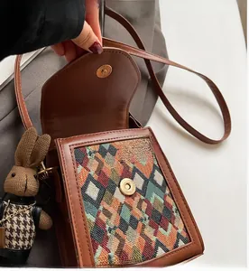 Detail of the brown vintage crossbody bag showing magnetic closure and woven bunny pendant