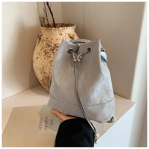 Detail of silver bucket bag with metallic crinkle texture, butterfly buckle and pearls