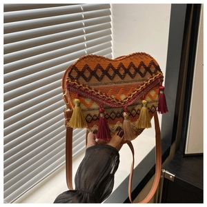 Detail of heart-shaped woven crossbody bag with ethnic patterns and colorful tassels