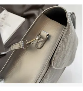 Close-up of shiny metal hardware and silver textured fabric on a women crossbody bag