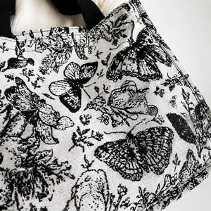 Gros plan sur la maille jacquard à motifs papillons noir et blanc de ce sac cabas