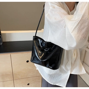 Detail of a chic black patent leather shoulder bag with a stylish bow decoration