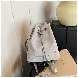 Detail of drawstring bucket bag with pleated texture, silver butterfly buckle and pearl charms