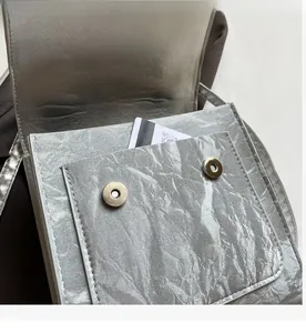 Macro shot of silver crinkled texture handbag showing interior pocket and magnetic closure