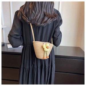 Detail of handmade woven bucket bag with yellow floral charms and colorful accents