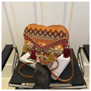 Detail of heart-shaped woven bag featuring geometric patterns and colorful tassels
