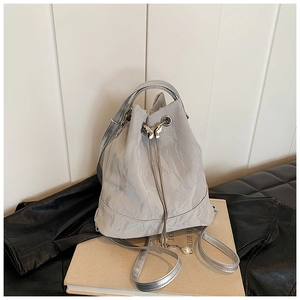 Close-up of silver drawstring bucket bag with butterfly buckle and pearl details