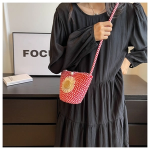 Detail of red and white woven crossbody bag with sunflower accent and pearl buckle
