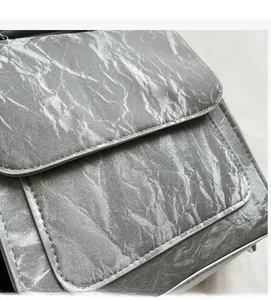 Close-up of silver crossbody bag featuring metallic textured fabric and refined stitching details