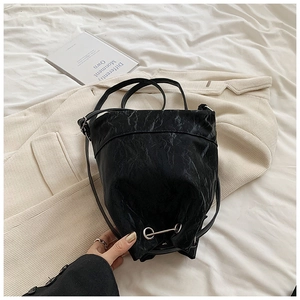 Detailed view of the wrinkled black leather texture and silver ring buckle on this bucket bag
