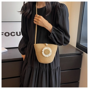 Detail of woven straw crossbody bag featuring sunflower decoration and pearl clasp