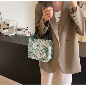 Close-up of a canvas tote bag with green butterfly prints on a cafe counter
