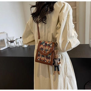 Detailed shot of a vertical crossbody bag with geometric pattern and rabbit charm