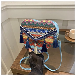 Detail of a heart-shaped woven bag with colorful geometric patterns and silk tassels