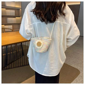 Detail of colorful woven straw crossbody bag with white daisy flower and pearl clasp