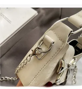 Detailed close-up of cream leather mini bag with silver bow hardware and chain strap