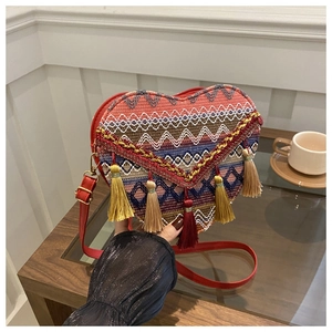 Macro shot of colorful woven heart bag with vibrant boho tassels and red leather strap