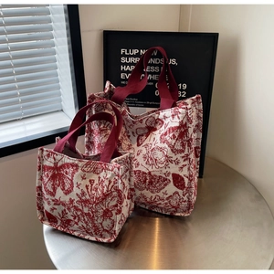 Detail view of retro red floral and butterfly print on cream canvas tote bag set