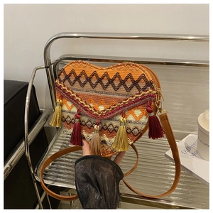 Detail of heart-shaped woven crossbody bag featuring colorful embroidery and tassel accents