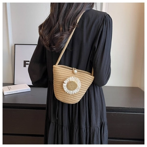 Detail of hand-woven straw bucket bag featuring a 3D daisy flower and pearl clasp closure