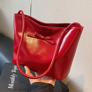 Glossy red patent leather tote bag for women featuring a stylish bow and slim handles