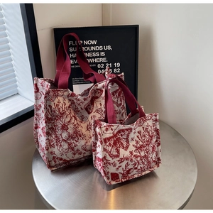 Detail of red floral toile pattern knit tote bags on a metal table in a retro setting