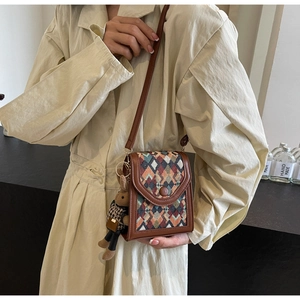 Detailed view of woven geometric crossbody bag with leather trim and rabbit charm