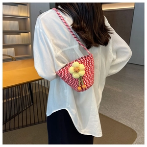Detail of red and white houndstooth woven crossbody bag with yellow flower charm