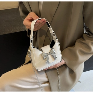 Close-up of a mini cream leather bow handbag with silver chain and metal hardware detail