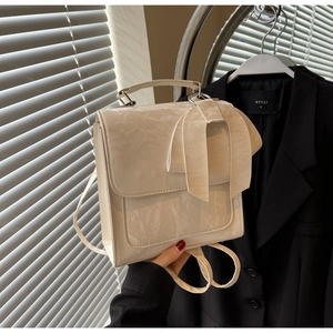 Detail of beige patent leather backpack featuring vintage textures and a large bow