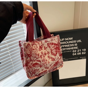 Close-up of knit tote bag with red butterfly embroidery and sturdy woven handles