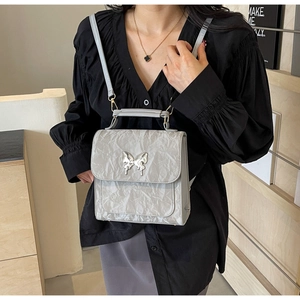Détail du sac à dos gris à texture froissée avec fermoir papillon et sangle réglable
