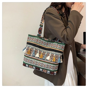 Detail of bohemian woven tote bag with geometric patterns and colorful tassel fringe