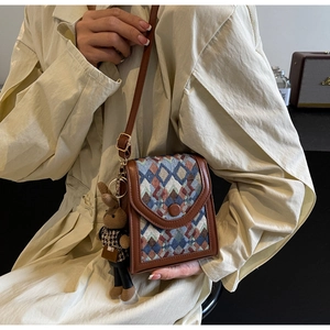 Detailed view of brown PU leather crossbody bag with plaid fabric and rabbit doll charm