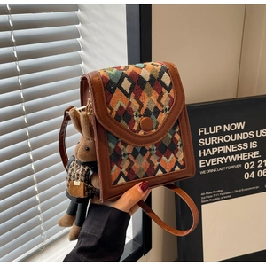 Detailed close-up of retro plaid woven crossbody bag with cute bunny doll charm